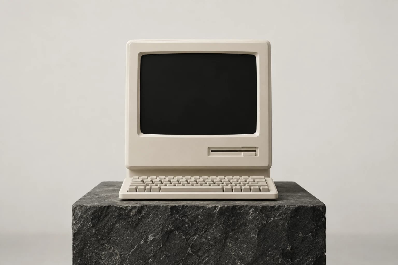An ivory retro computer and keyboard on a sculpted dark stone pedestal